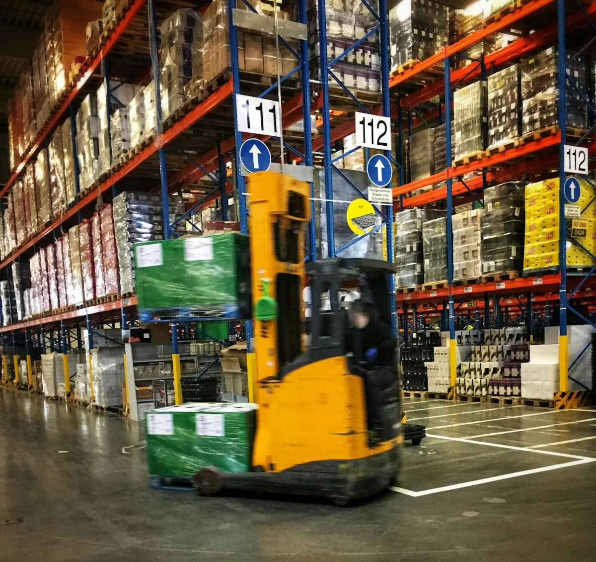 Forklift driving through a warehouse filled with pallets