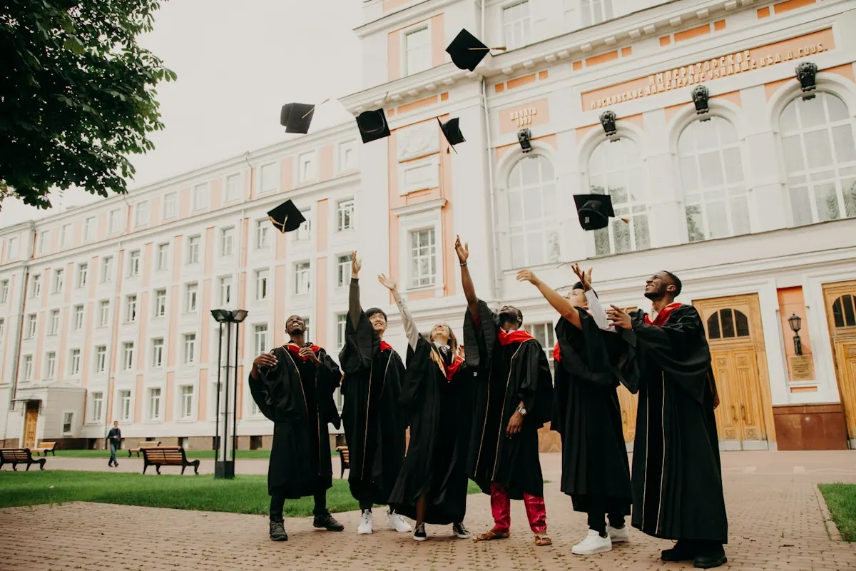 Graduates in black gowns throwing their caps in the air