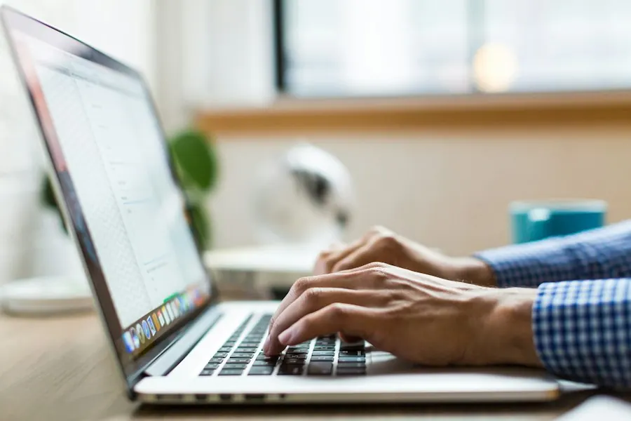 Person typing on a laptop while filling in an online form