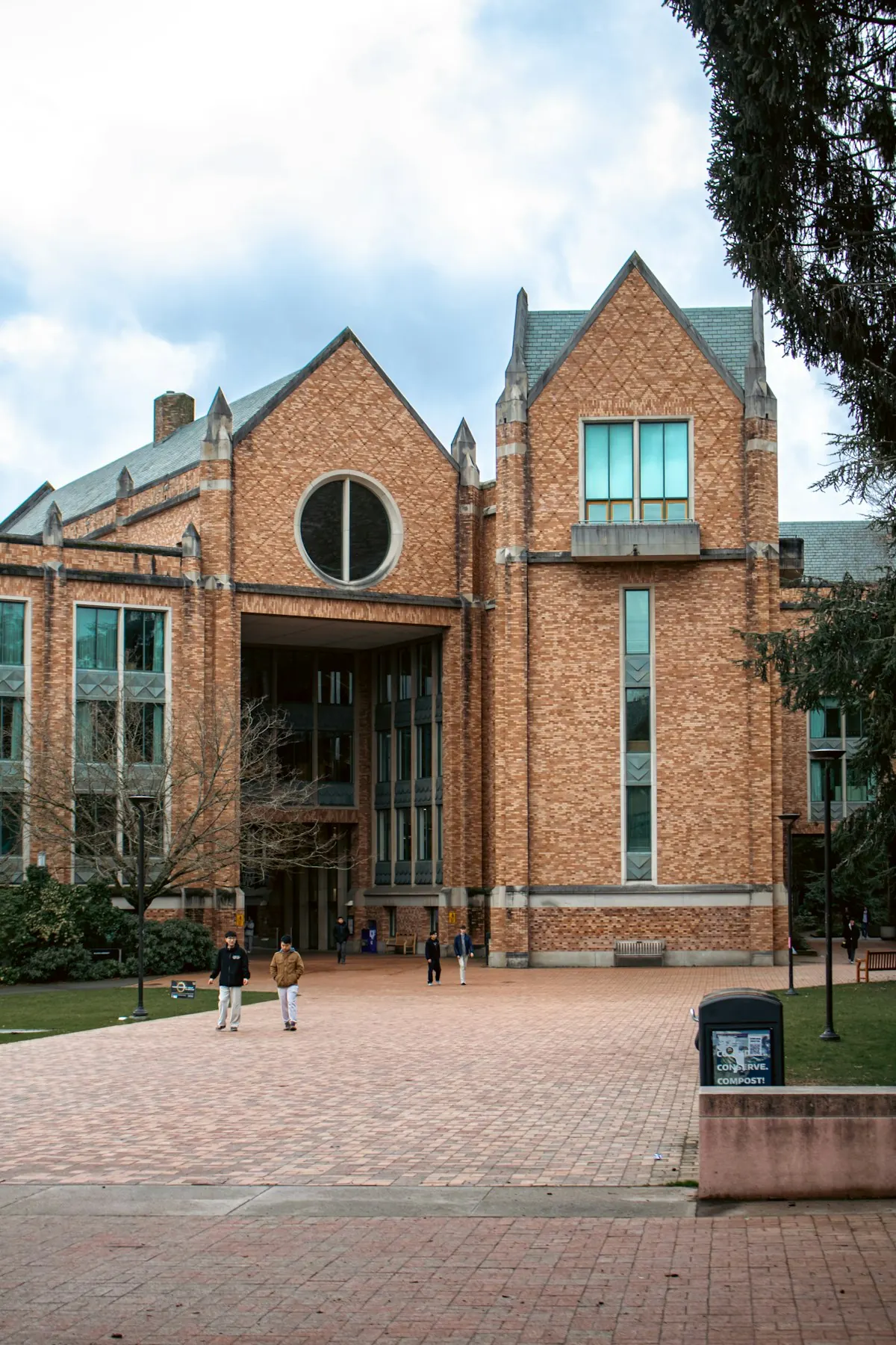 Students walking across a brick plaza in front of a university building
