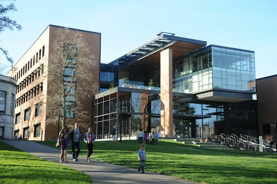 Students walking past a university hall on a sunny day