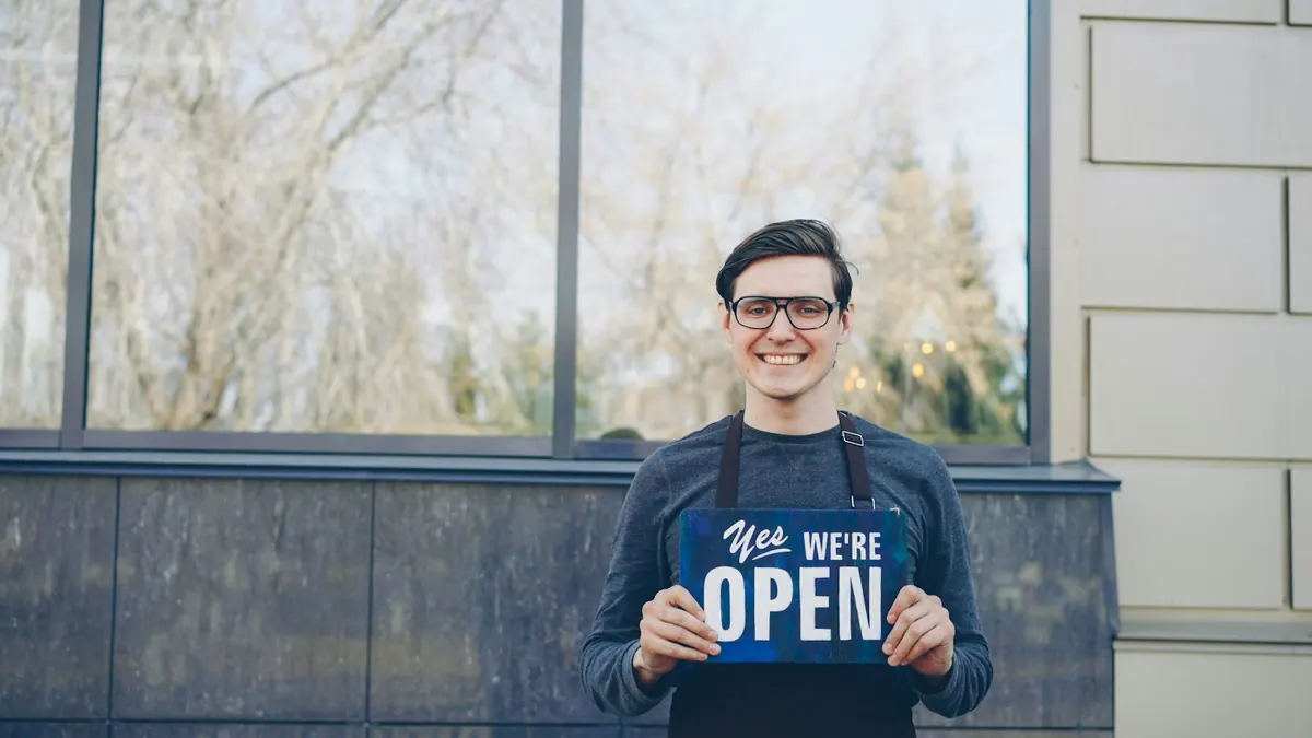 Smiling business owner holding a we're open sign