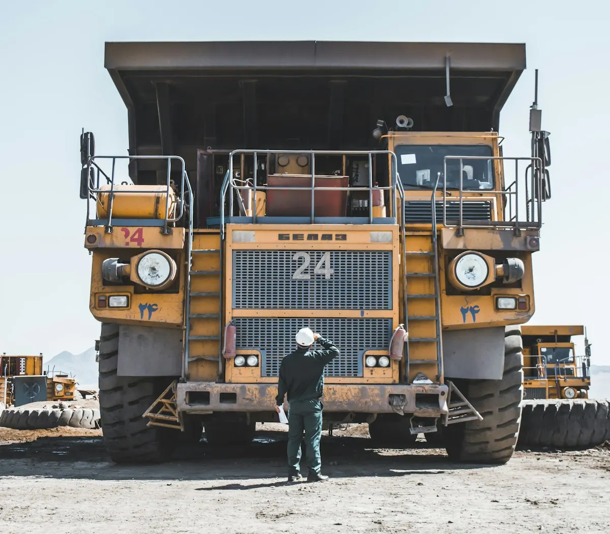 Equipment specialist standing beside a large yellow haul truck