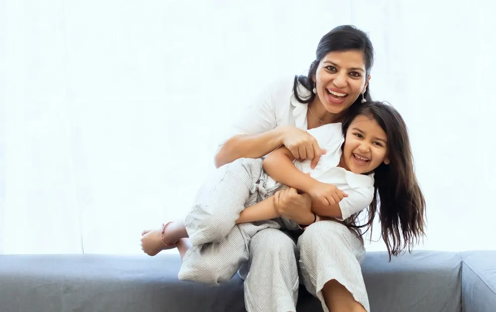Mother holding a laughing child on a sofa