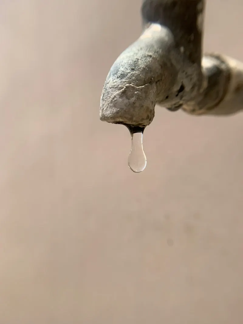 Old tap with a water drop and mineral build-up